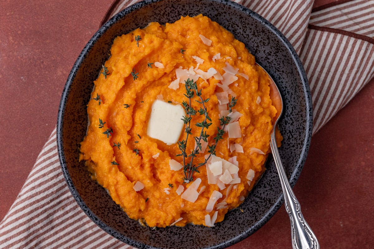 mashed butternut squash in a black bowl with a spoon