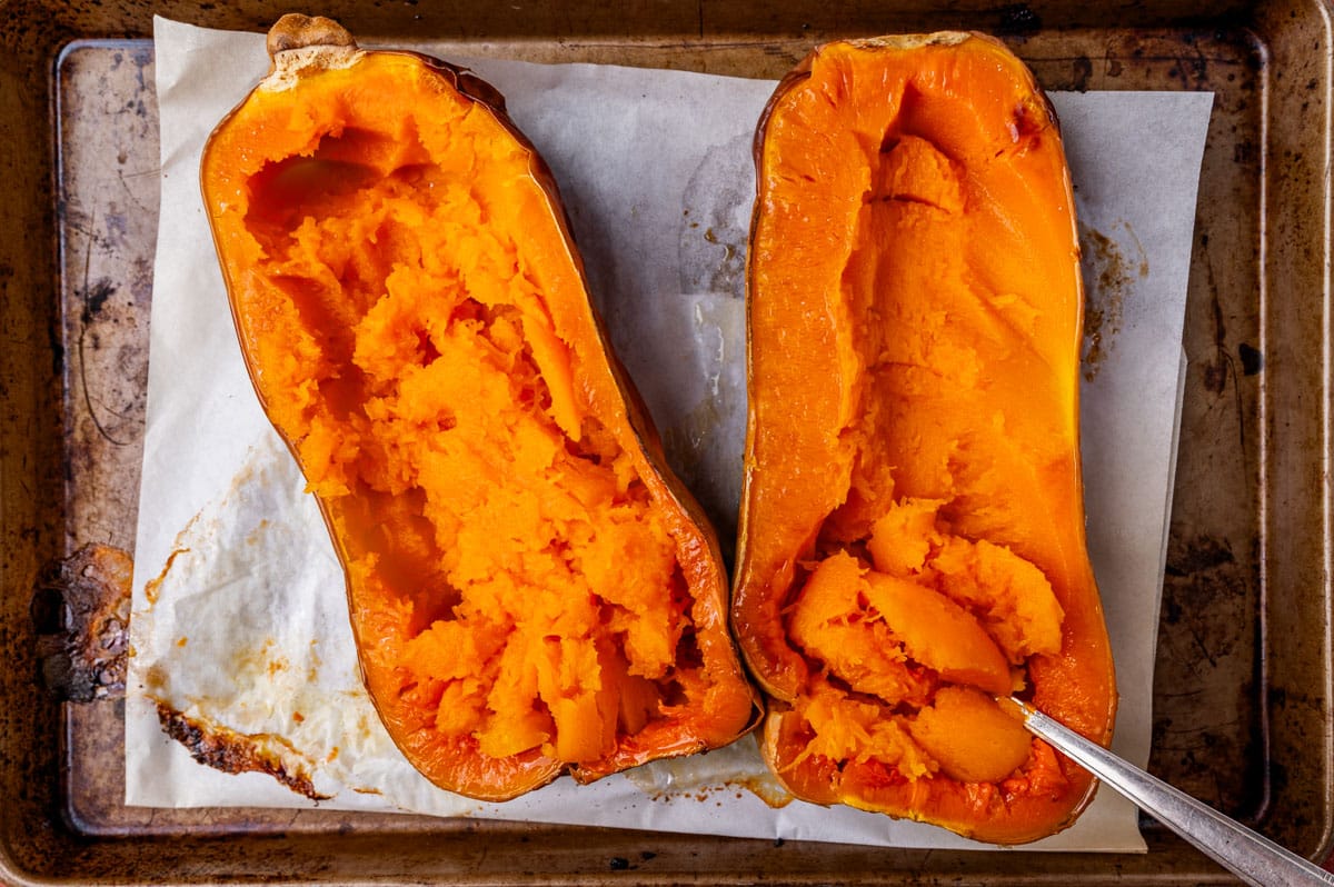 a baked butternut squash cut in half on a baking sheet