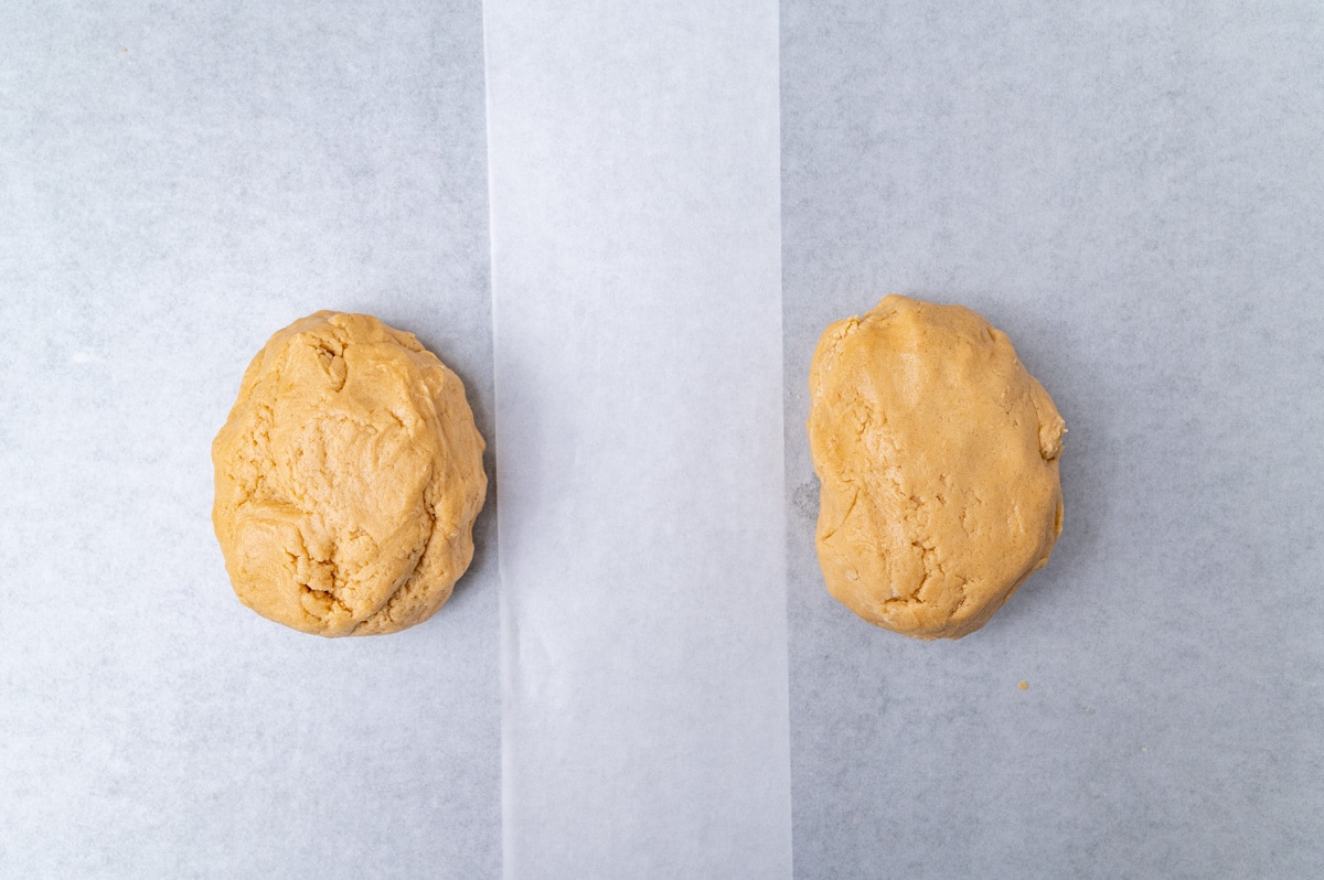 two balls of peanut butter cookie dough on parchment paper