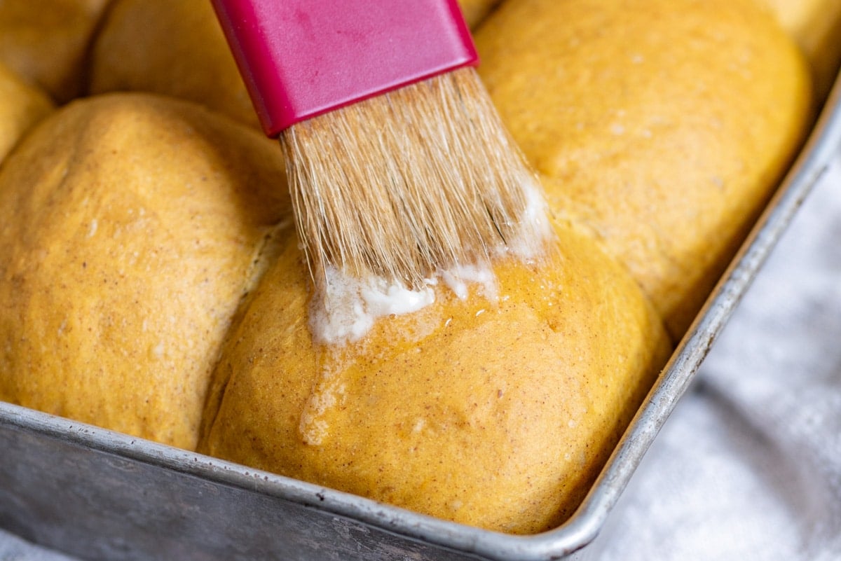 butter spreading on the top of a warm pumpkin roll