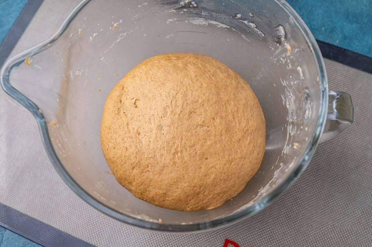 pumpkin yeast rolls dough in a glass bowl