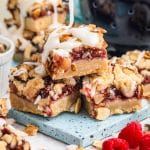 a stack of 3 almond raspberry bars with glaze drizzling on top