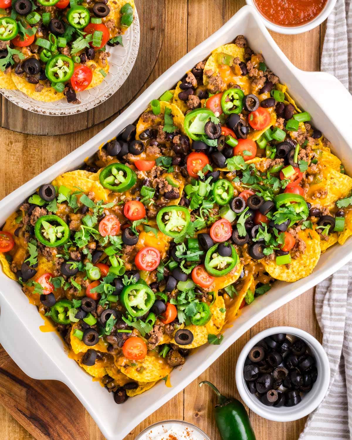 baked nachos in a baking pan with fresh vegetables on top