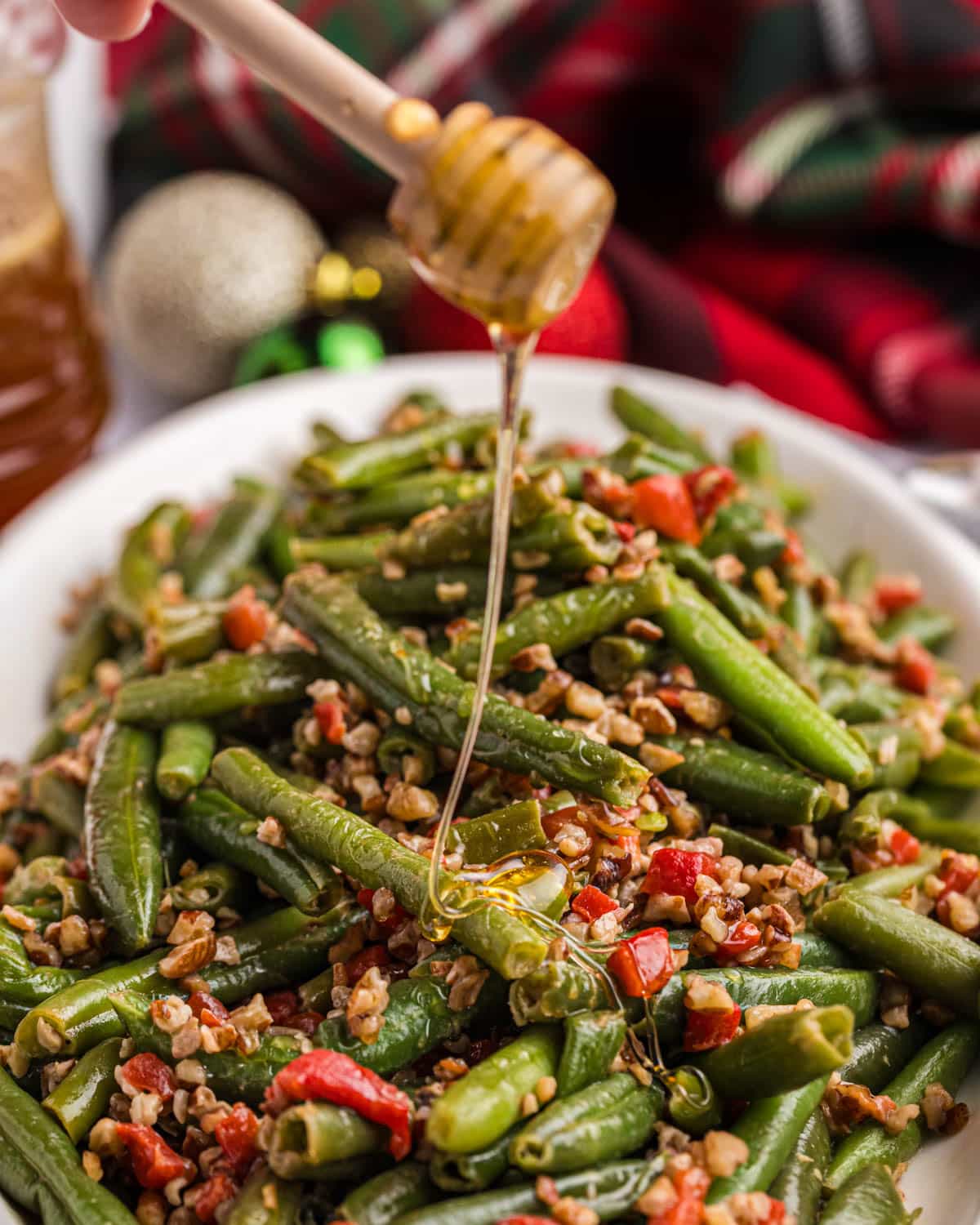 honey drizzling over green beans with pimentos and pecans