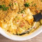 closeup of cheesy potatoes in a baking dish with a spoon