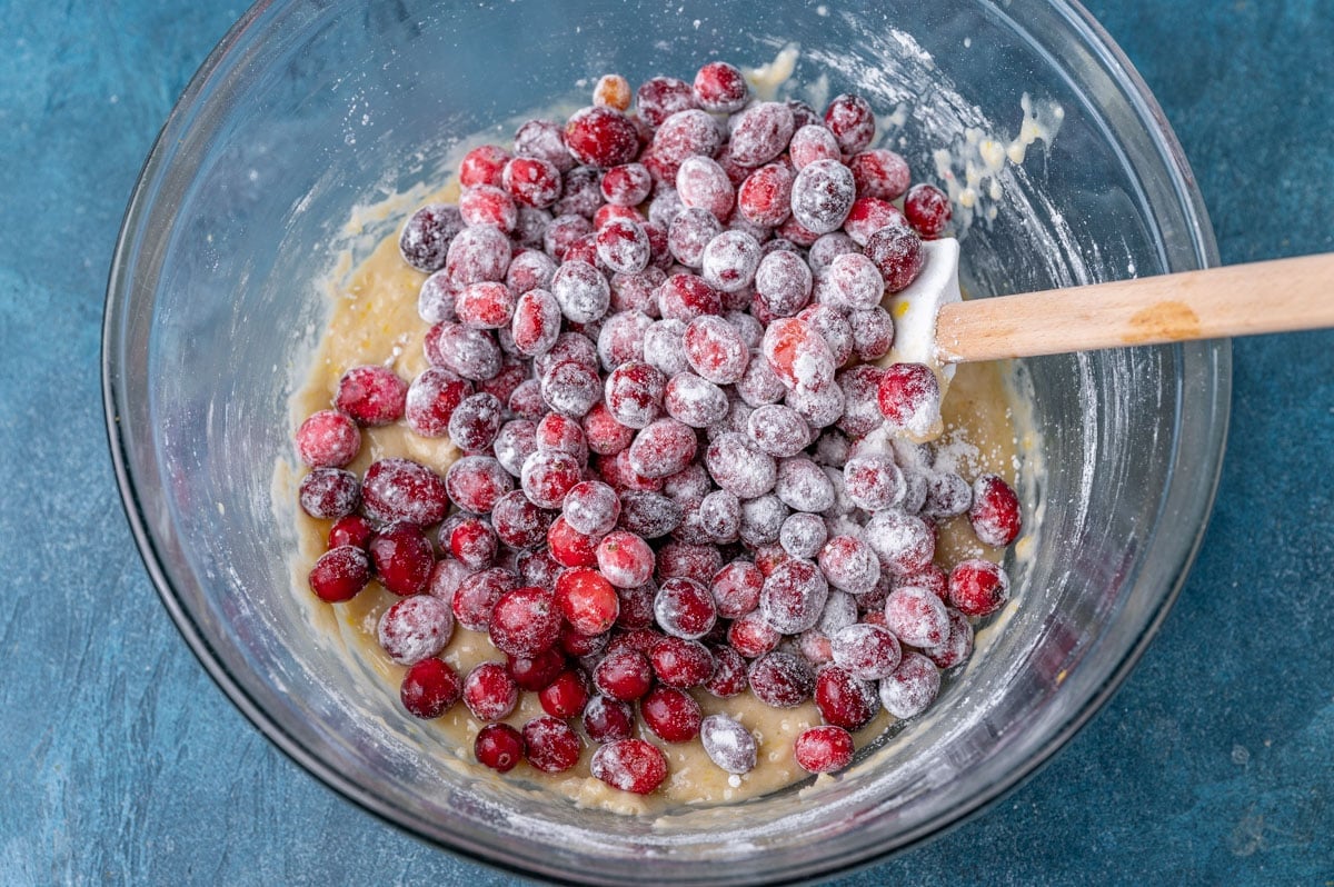 floured cranberries in a bowl with a spatula