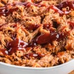 closeup of a bowl of dr pepper pulled pork with bbq sauce on it
