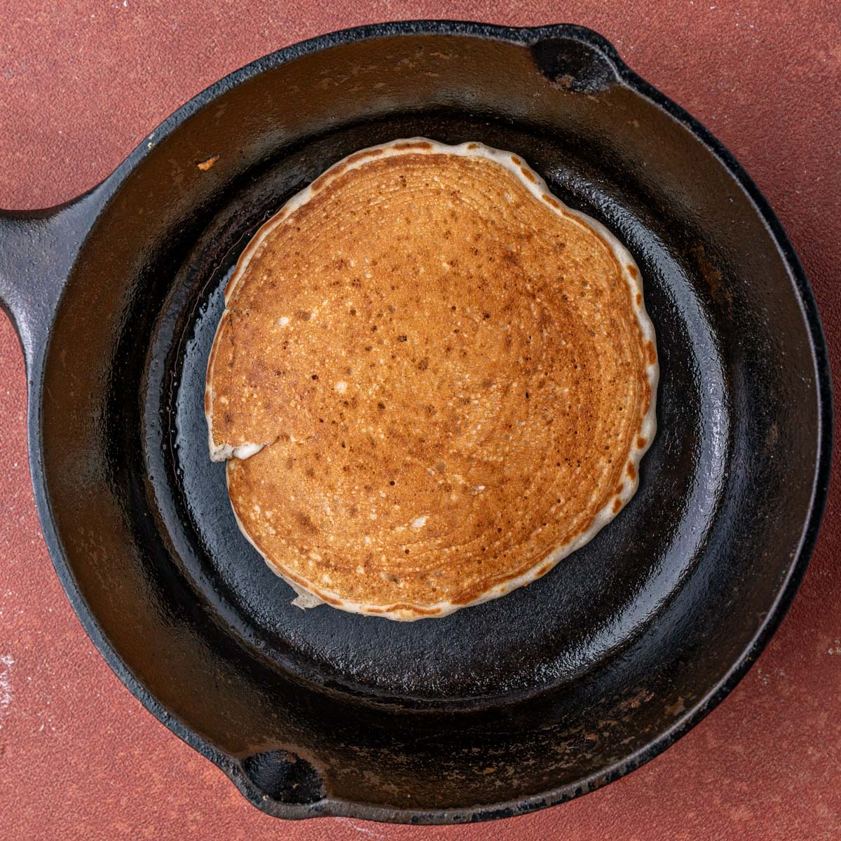 a golden brown pancake in a cast iron skillet