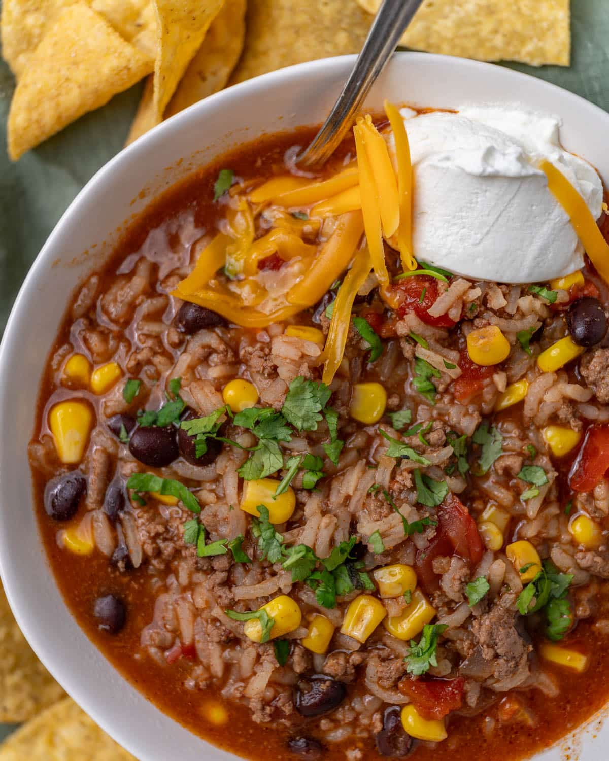 a bowl of mexican beef and rice soup with cheese and sour cream