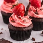 a chocolate cupcake with strawberry frosting and a strawberry sitting on top