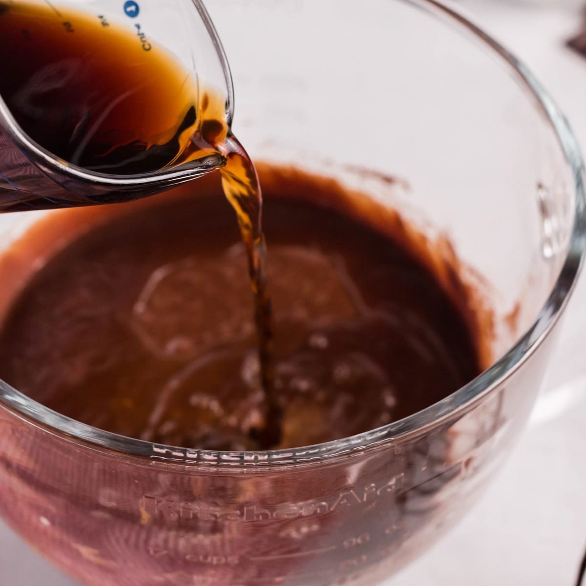 coffee pouring into chocolate cake batter in a bowl