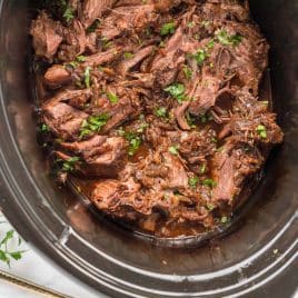 overhead view of shredded pot roast in a slow cooker