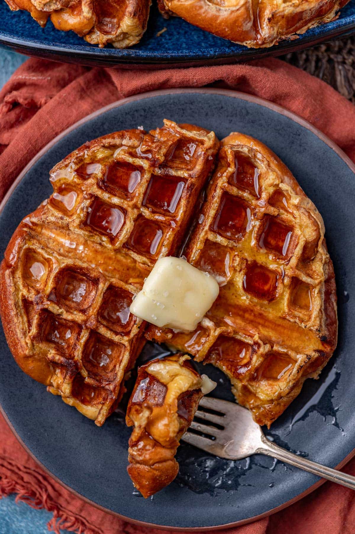 a challah waffle on a plate with one bite on a fork