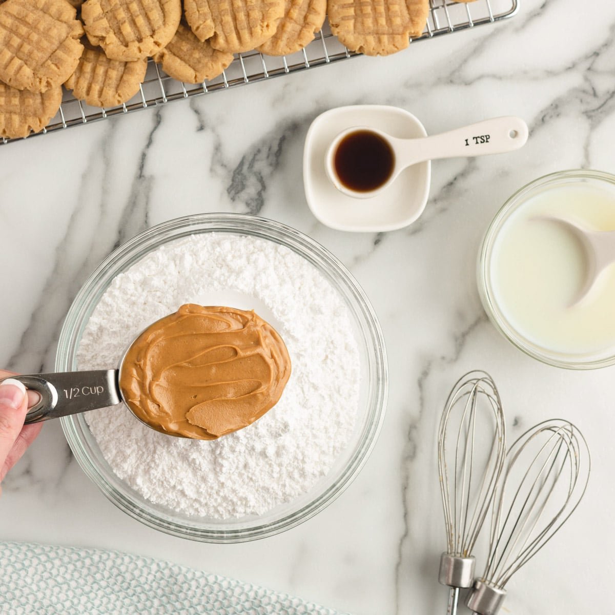 peanut butter in a measuring cup over powdered sugar on a table