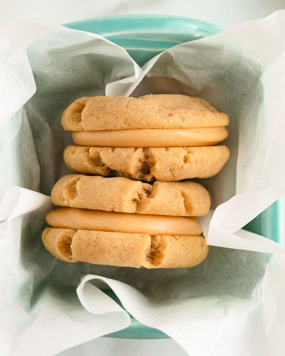two peanut butter cookie sandwiches in a pan with parchment paper