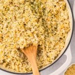 closeup of orzo rice pilaf in a skillet with a wooden spoon