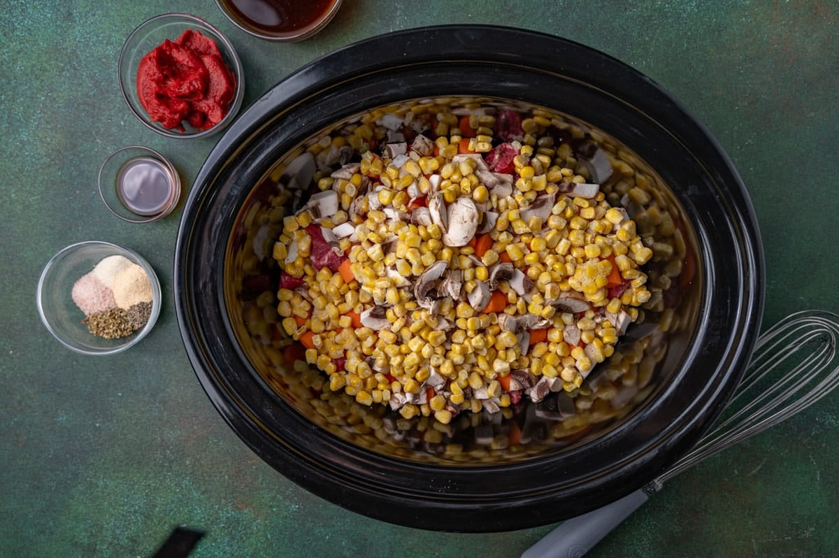 corn, mushrooms, beef and carrots in a slow cooker