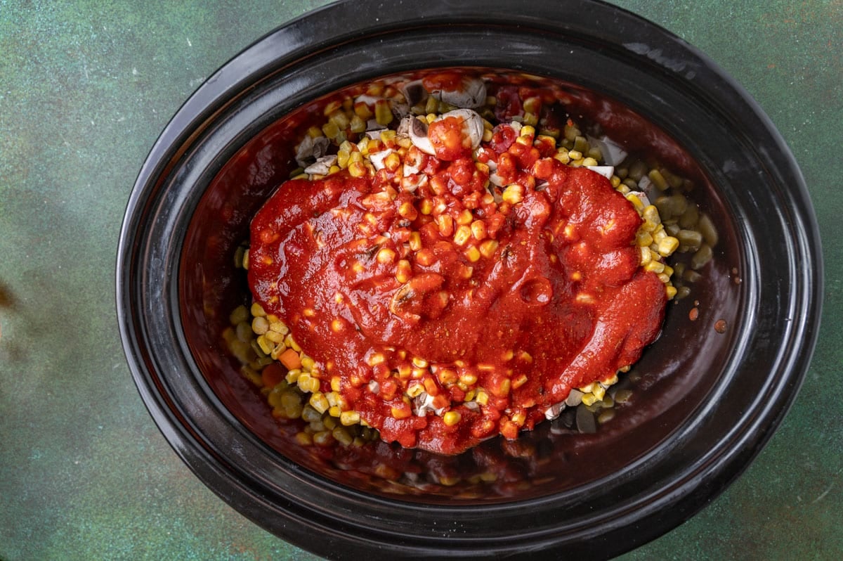 tomato sauce over veggies in a slow cooker