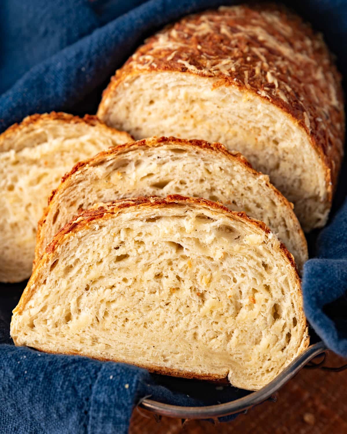 a loaf of asiago cheese bread cut in slices in a basket