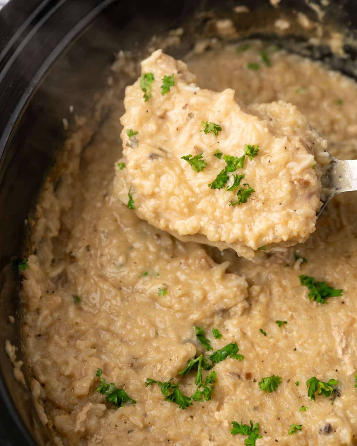 a pork chop cooked in creamy rice in a slow cooker