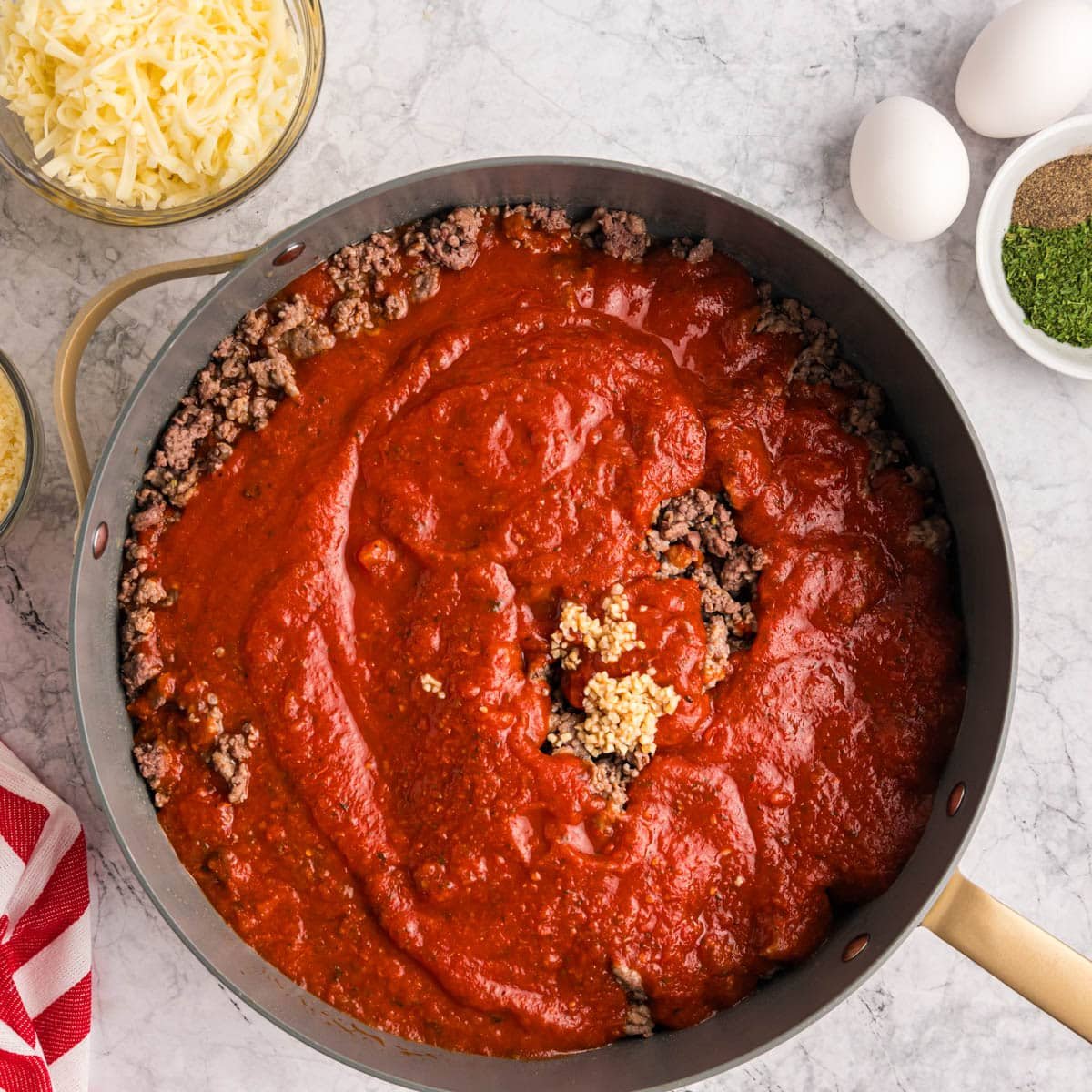 browned meat with garlic and spaghetti sauce over the top