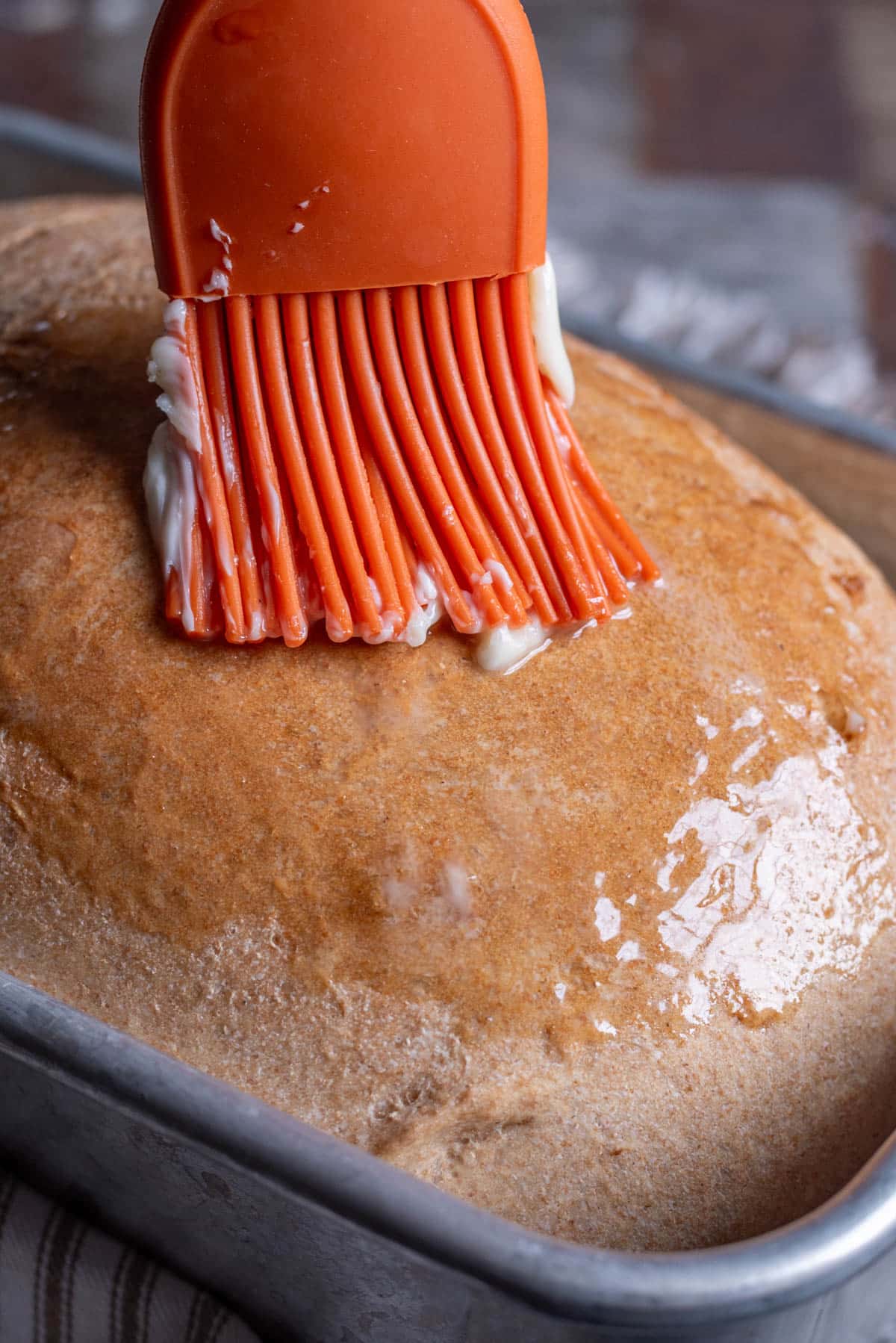 butter brushing over a loaf of honey wheat bread