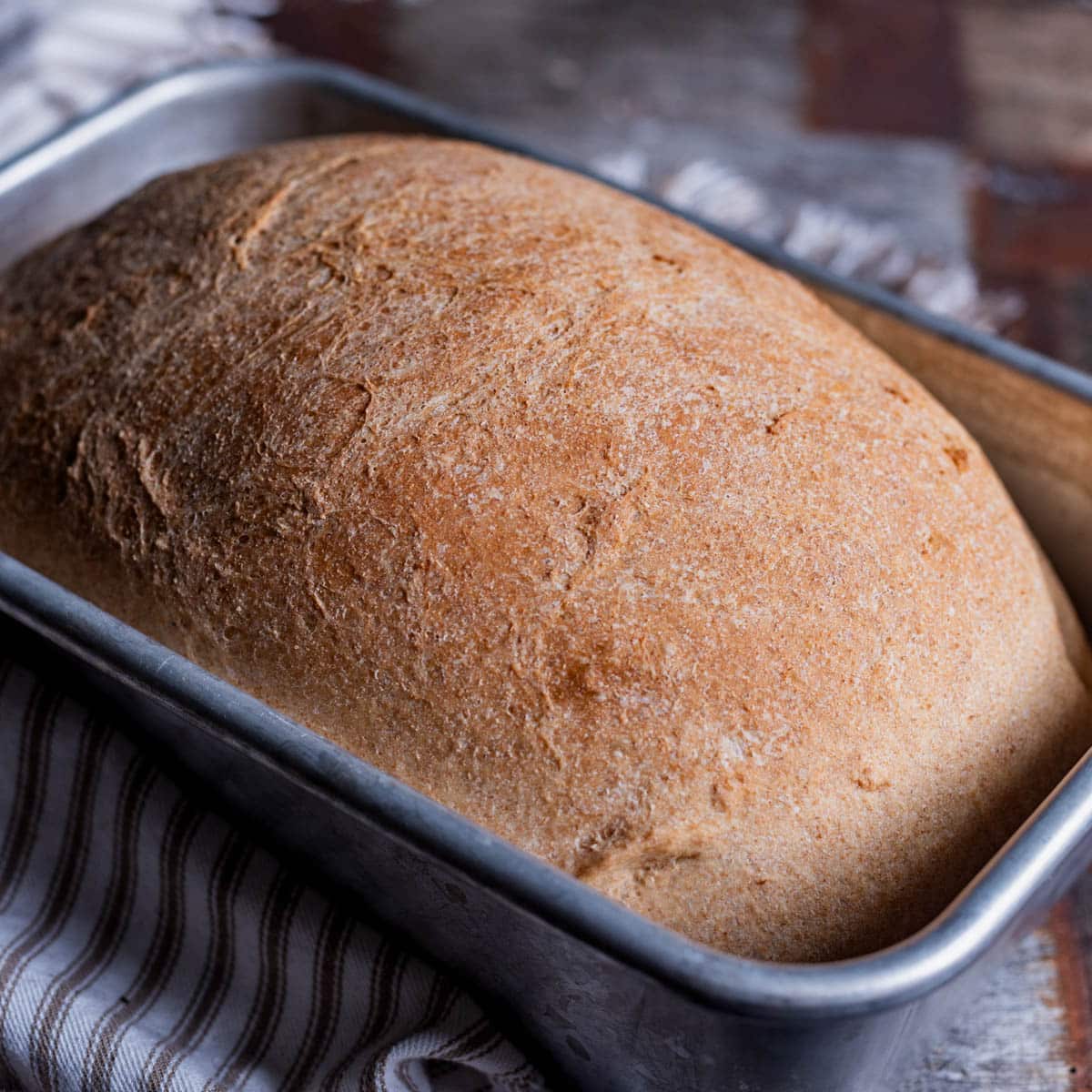 a loaf of honey wheat bread in a loaf pan