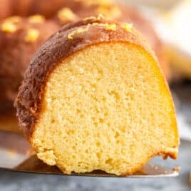 a slice of lemon bundt cake on a spatula with lemon zest on top