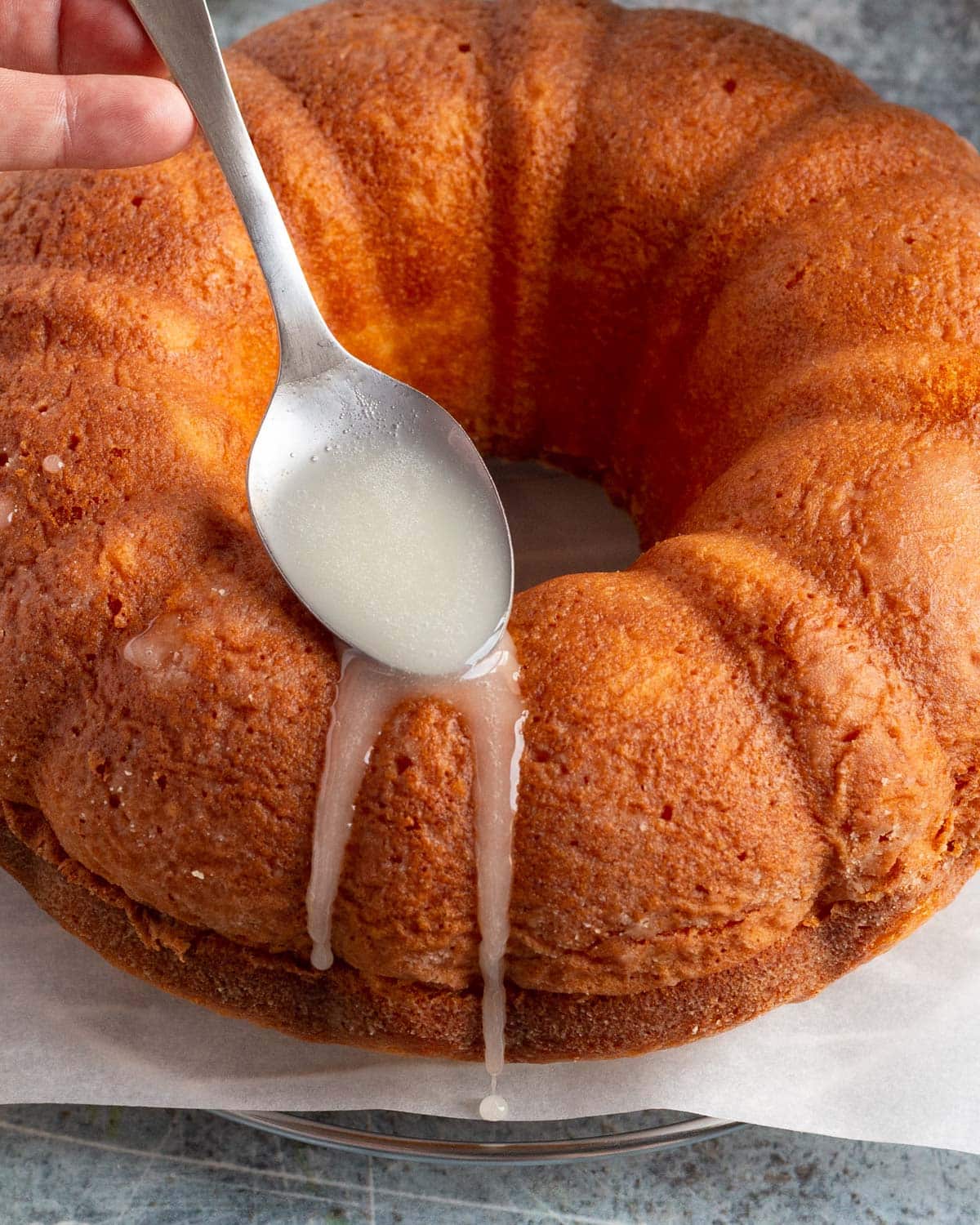 spooning lemon glaze over a lemon bundt cake