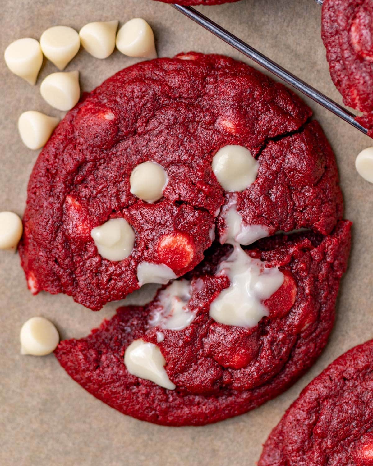 a red velvet cookie broken in half with white chocolate chips