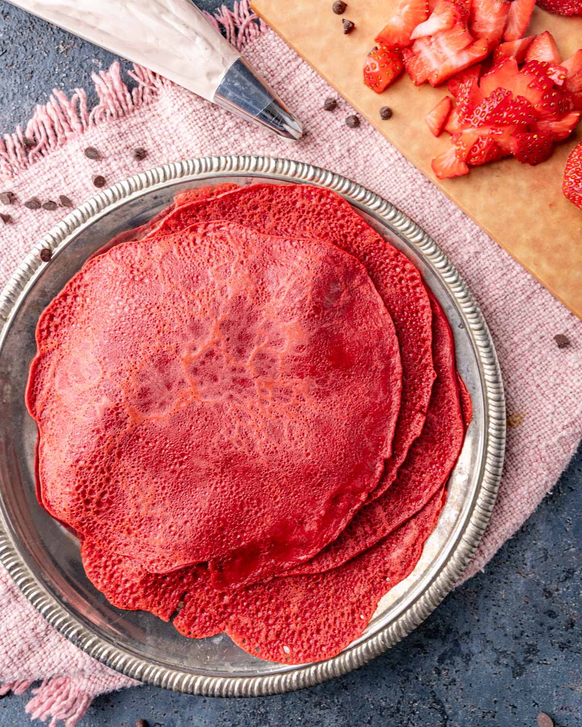 a plate with red velvet crepes stacked on top