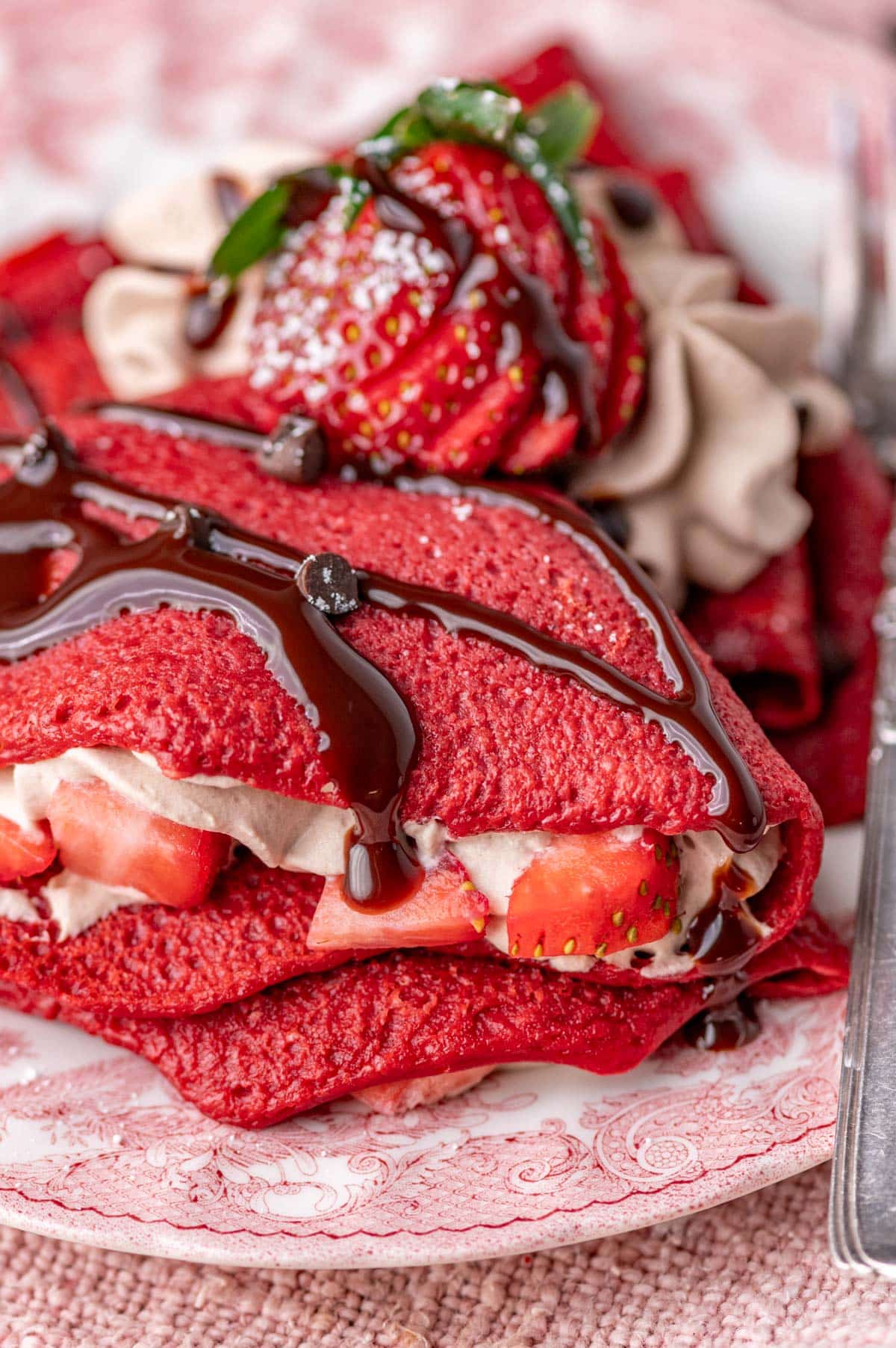 a plate of red velvet crepes with chocolate sauce