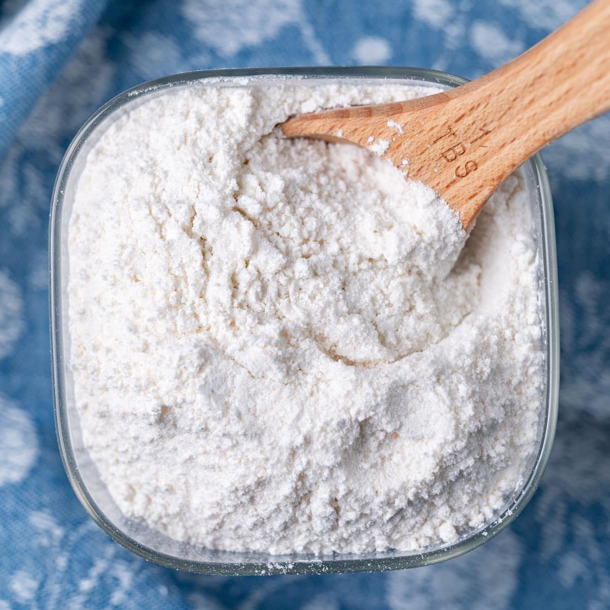 overhead view of homemade pudding mix on a glass container with a wooden spoon