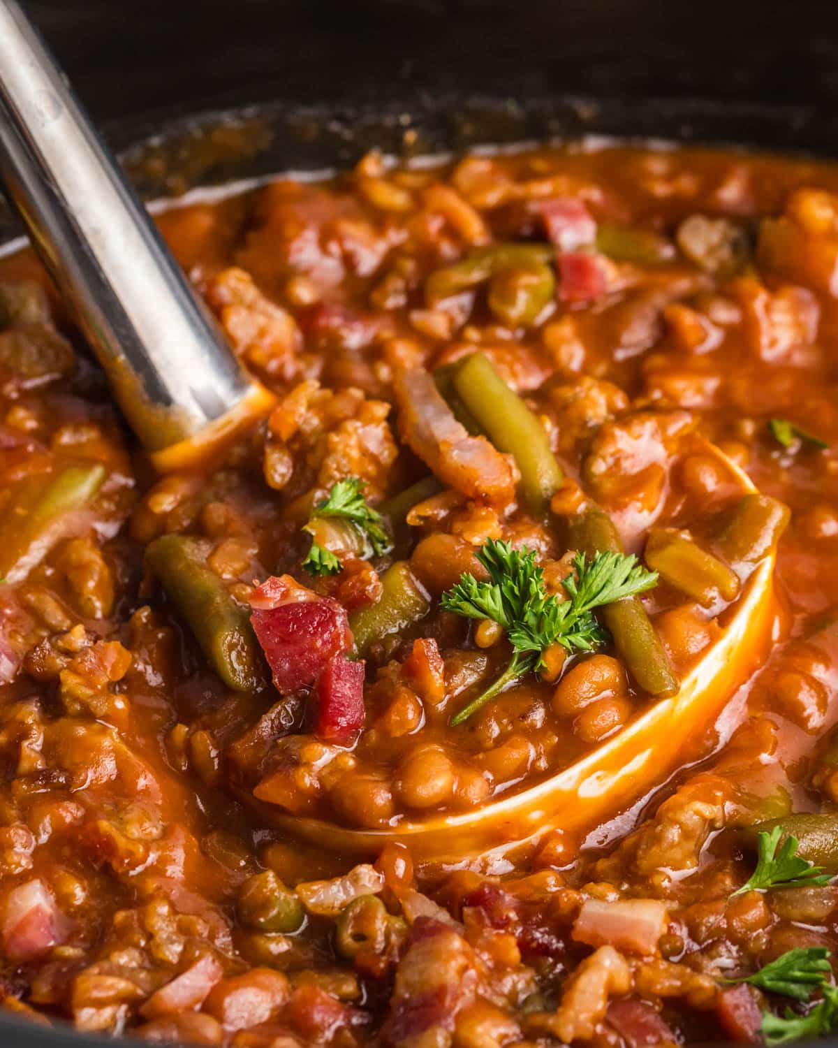 a ladle full of sausage and green bean casserole in a slow cooker