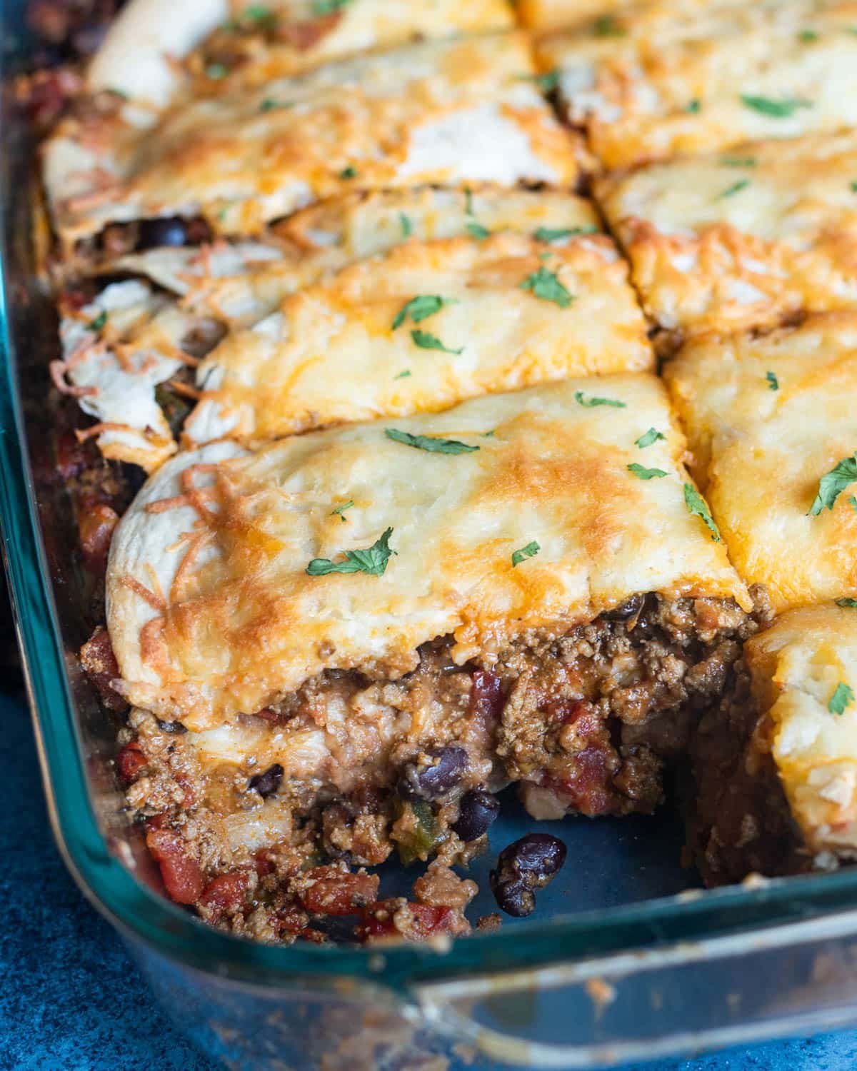 9x13" glass baking pan with taco lasagna, one slice missing