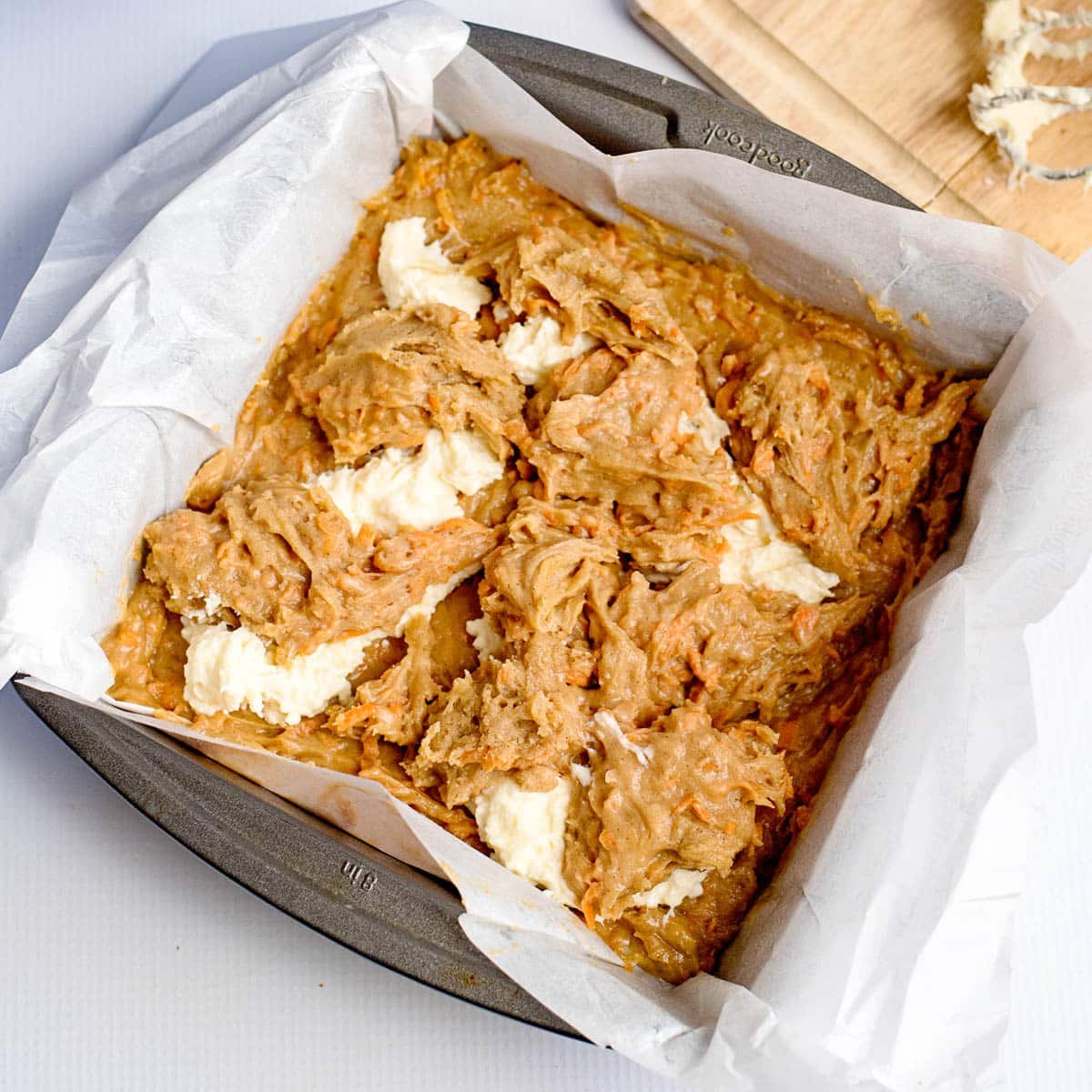 carrot cake batter and cheesecake batter in a square pan