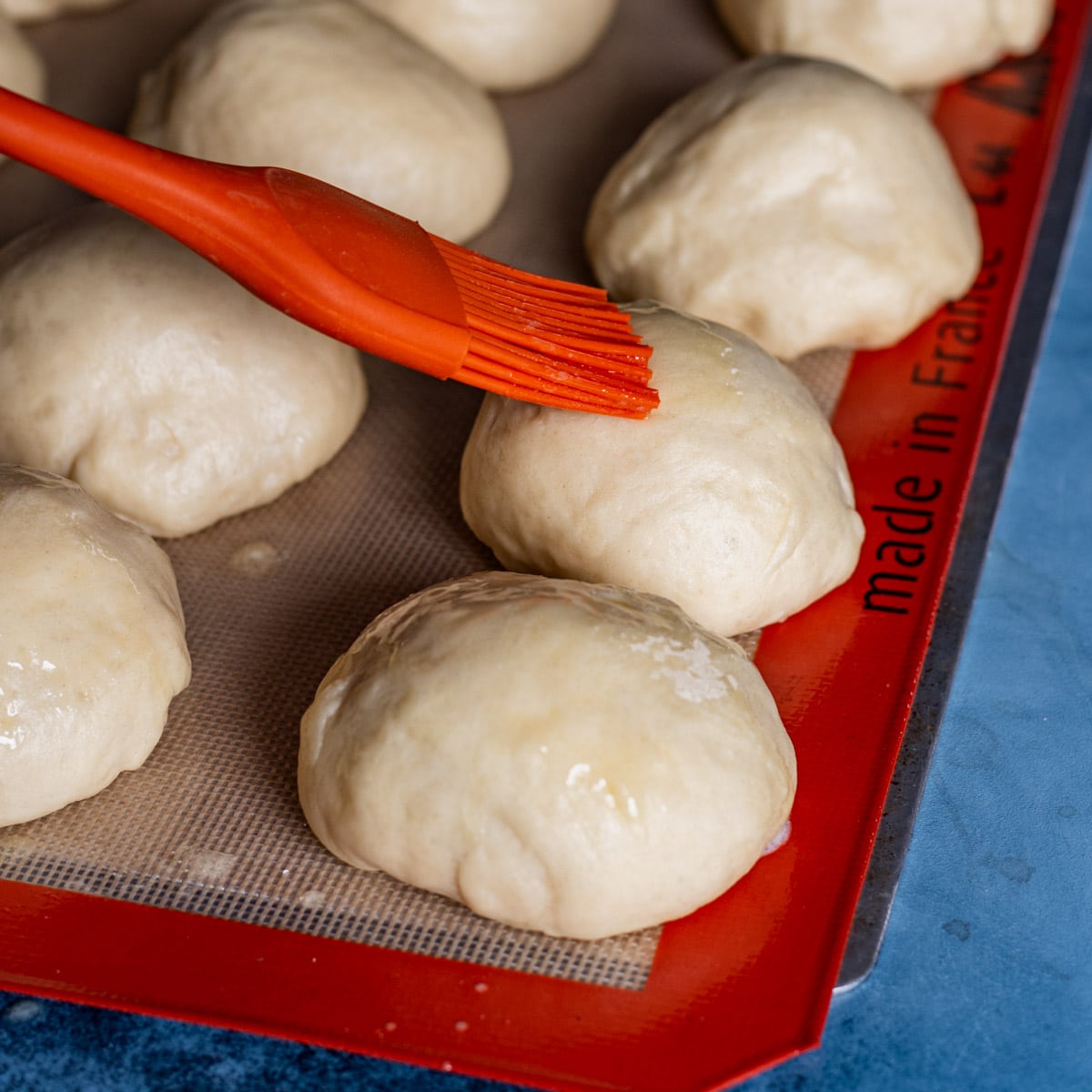 brushing butter over dough balls