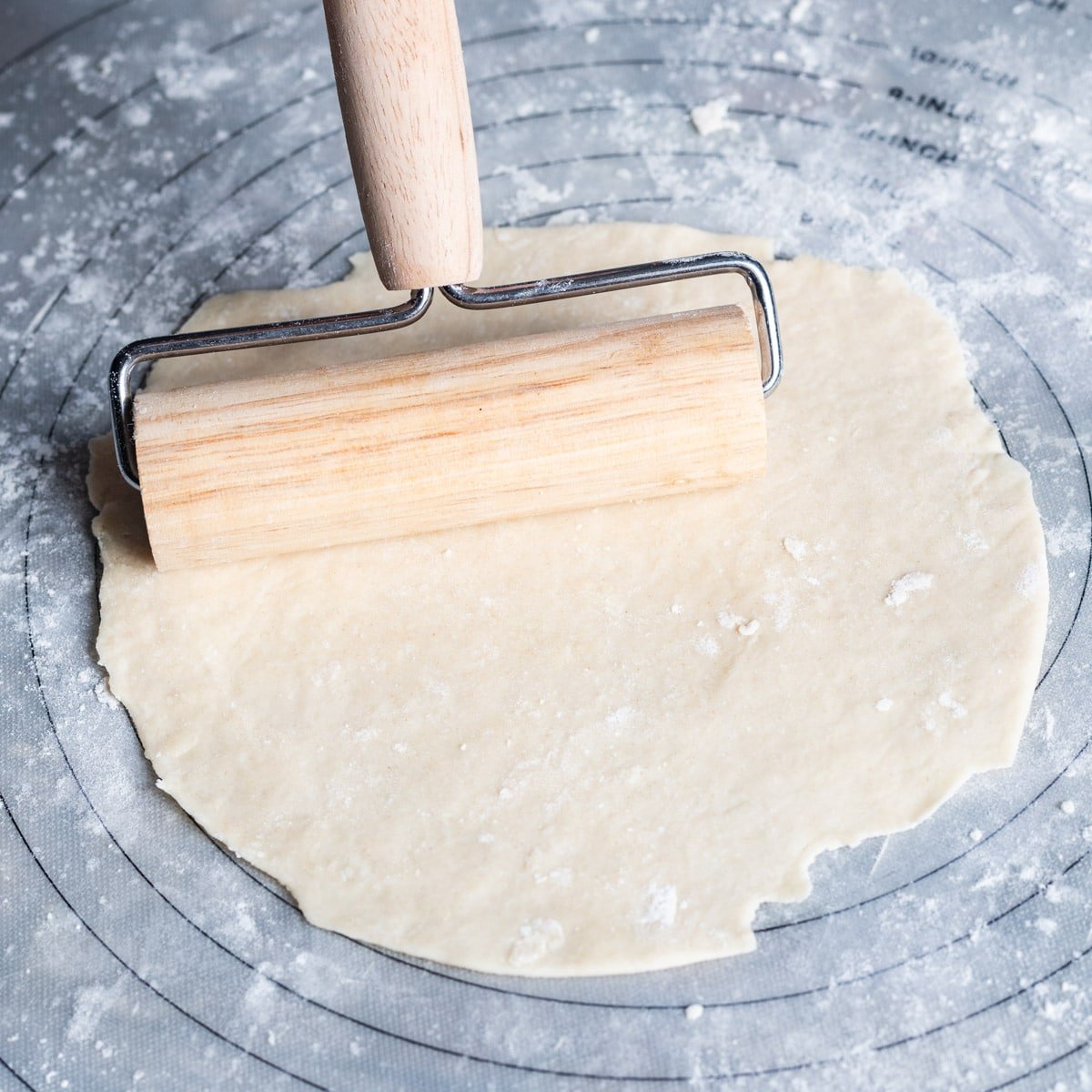 a rolling pin rolling a flour tortilla into a circle