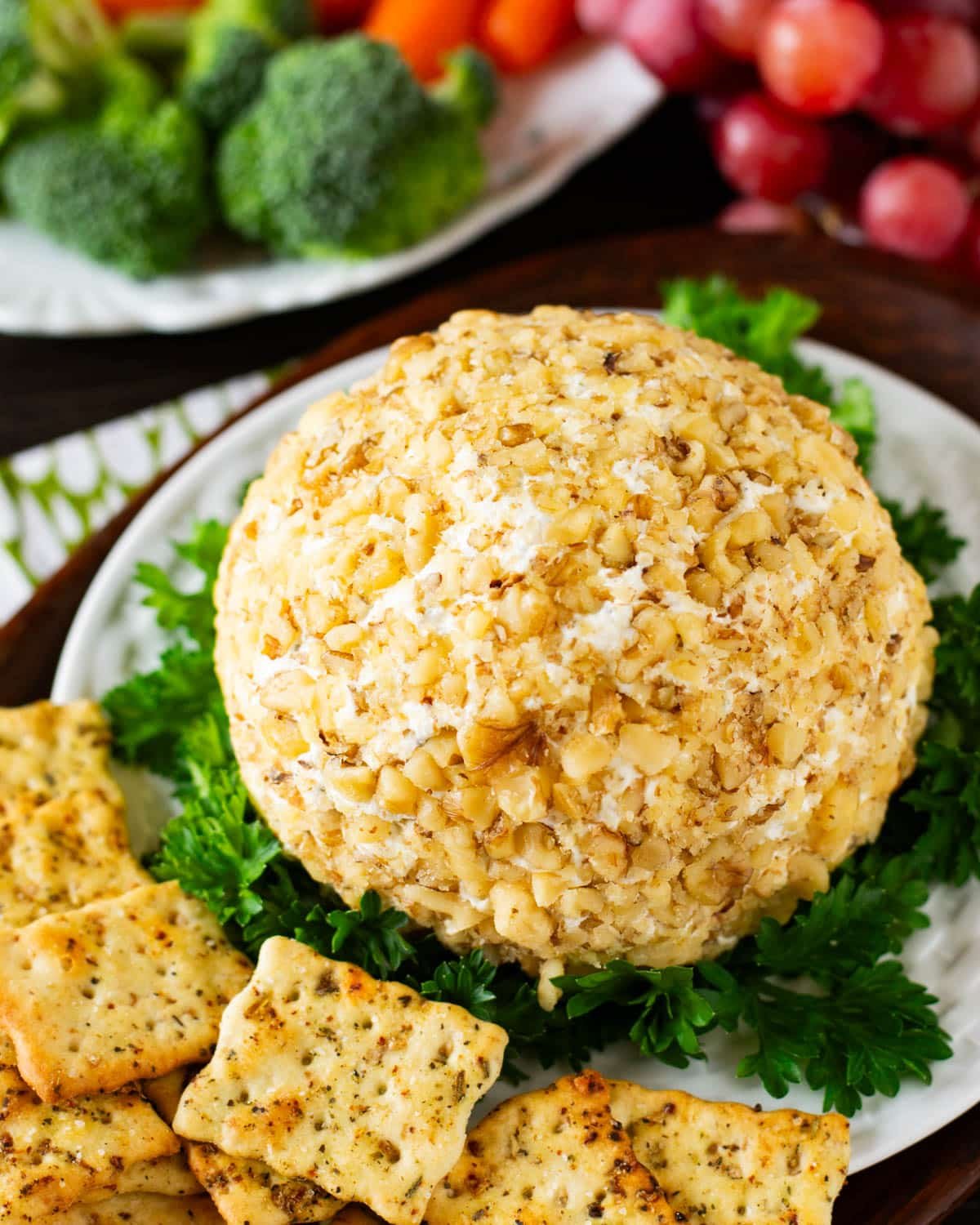 a cheese ball on a plate with parsley and crackers