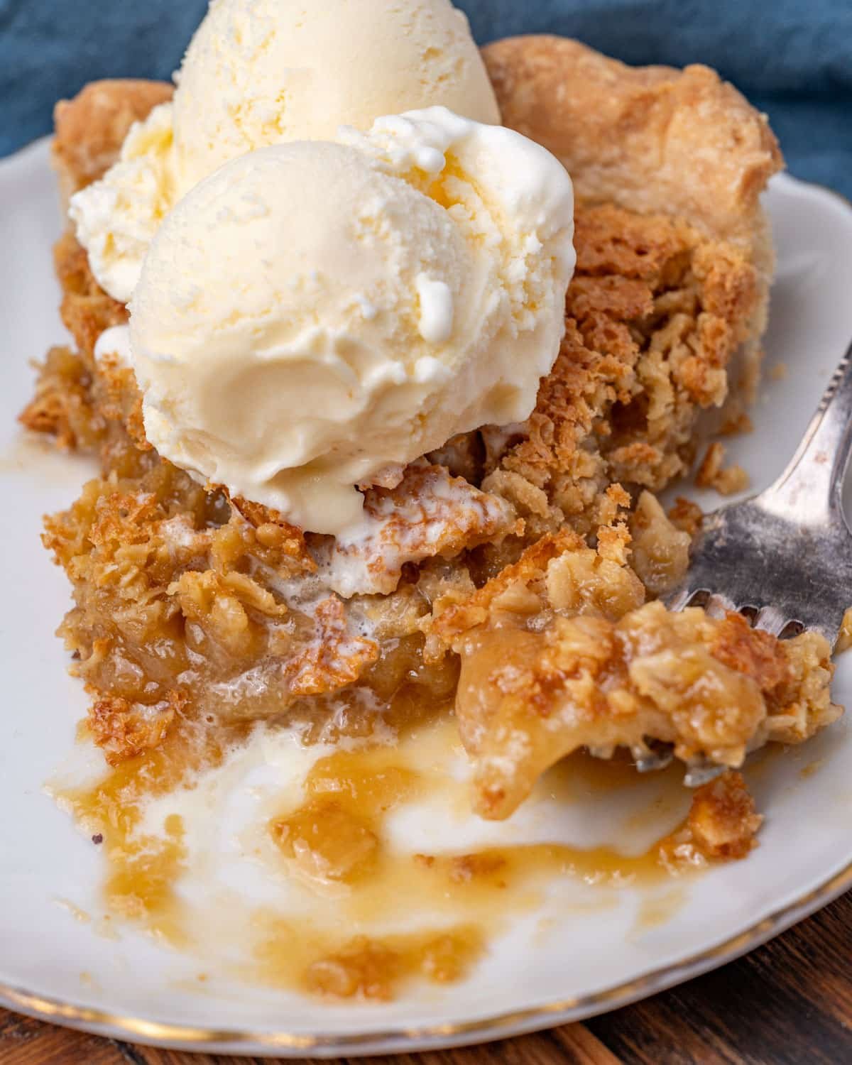 a piece of pie with ice cream and a bite on a fork
