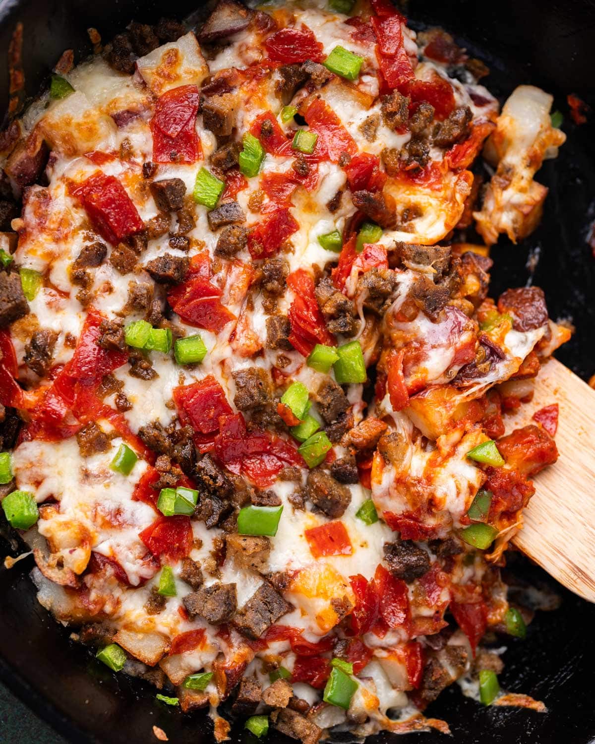 overhead view of pizza skillet potatoes with a wooden spatula