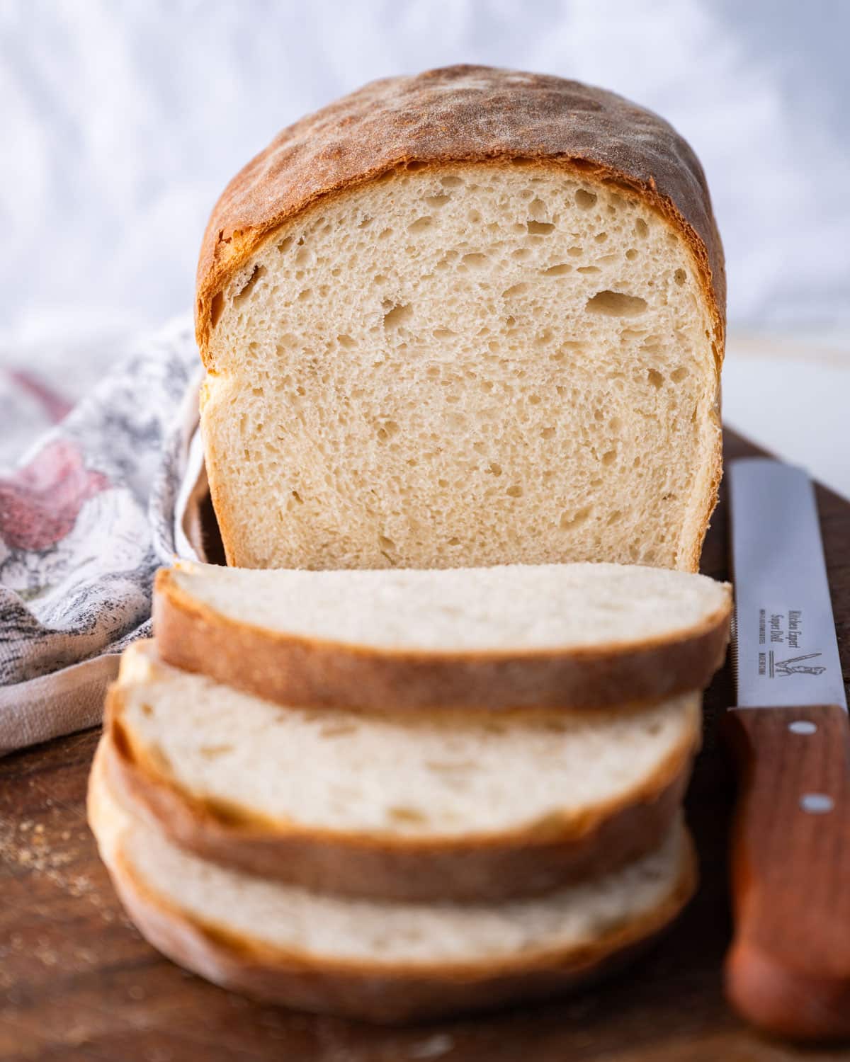 a loaf of country white bread on a cutting board with slices cut