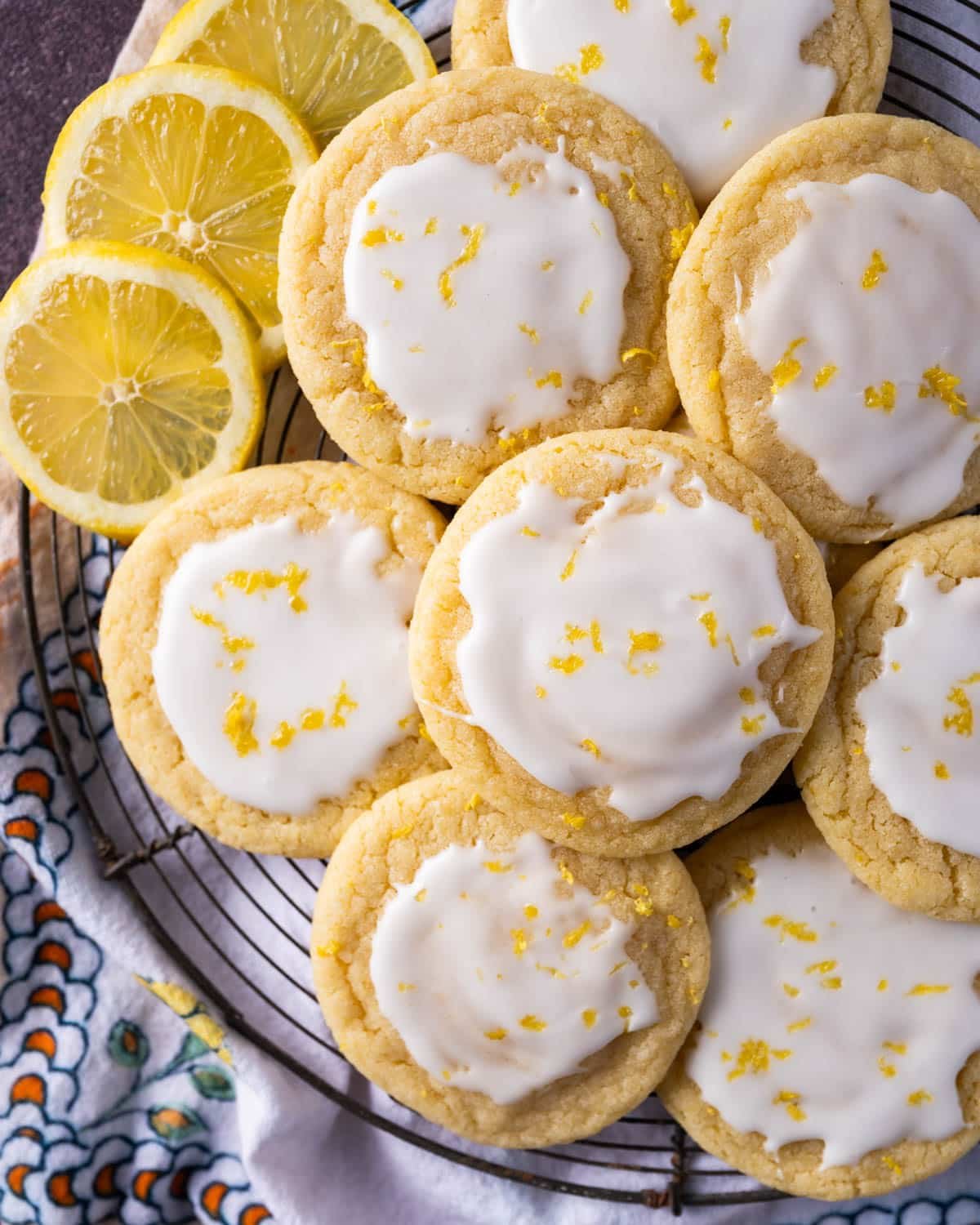 lemon sugar cookies on a rack with slices of lemon