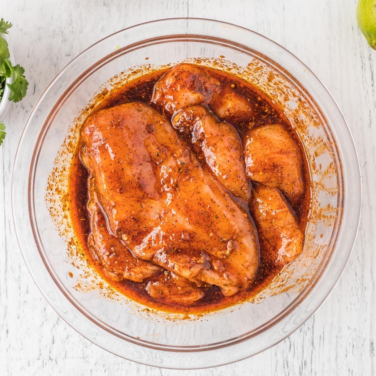 chicken marinating in a bowl with mexican seasoning