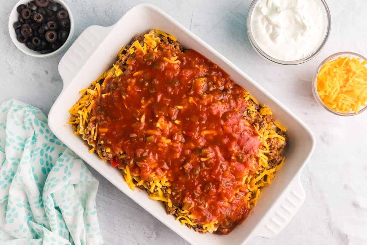 unbaked mexican lasagna in a white casserole dish
