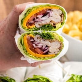 closeup of a hand holding a lettuce wrap cut in two pieces