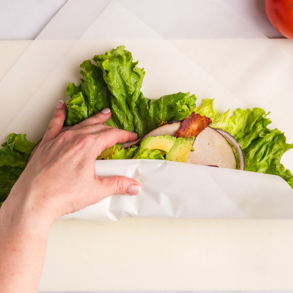 rolling a lettuce wrap in parchment paper