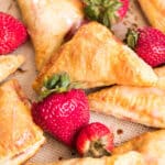 closeup of strawberry turnovers on a baking mat with fresh strawberries