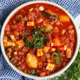 overhead view of a bowl of summer chili with fresh herbs on top