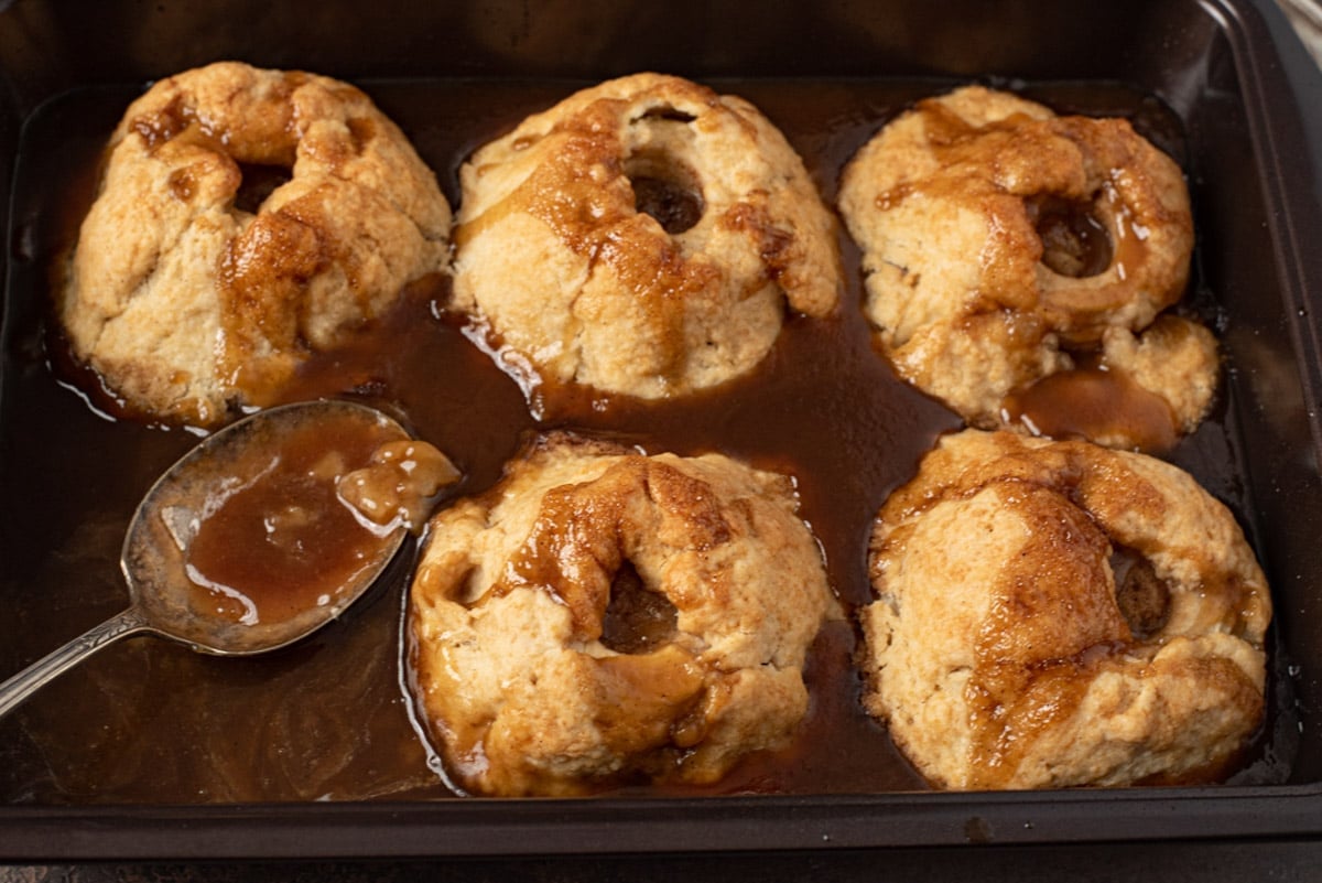 5 apple dumplings in a pan with brown sugar syrup